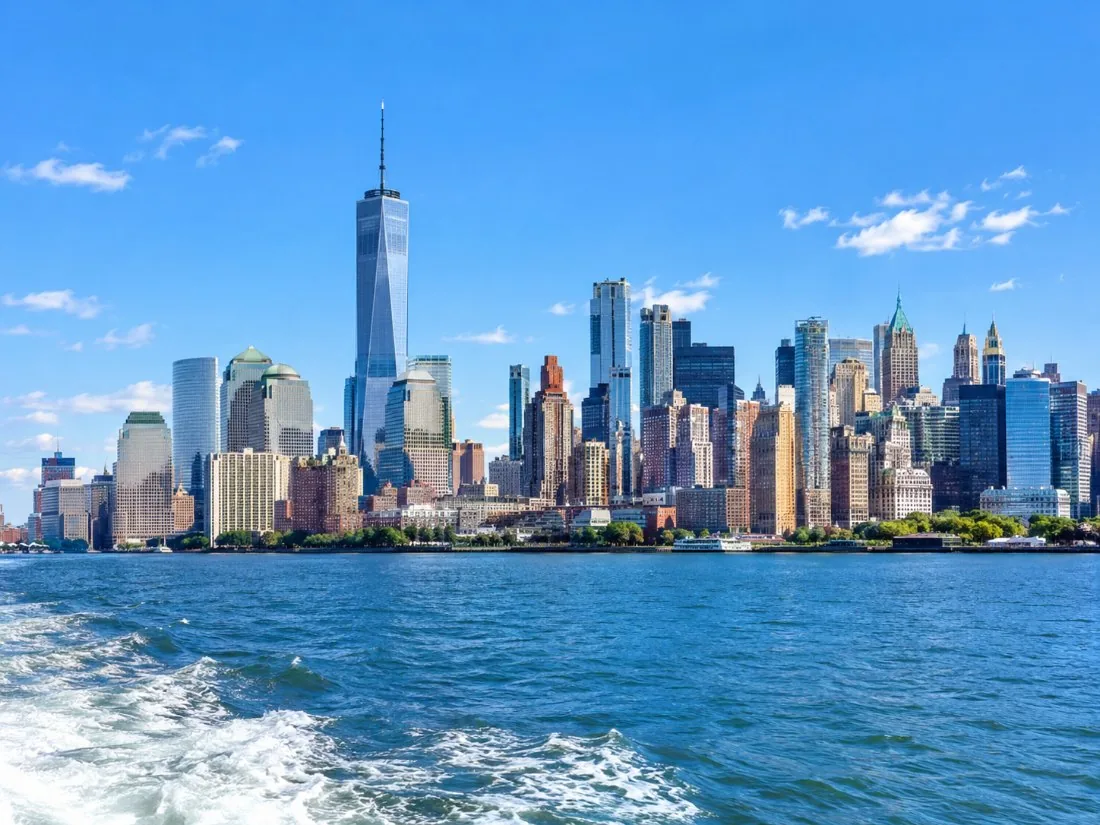 El horizonte de Lower Manhattan elevándose sobre las aguas azules del puerto, visto desde la cubierta de un barco
